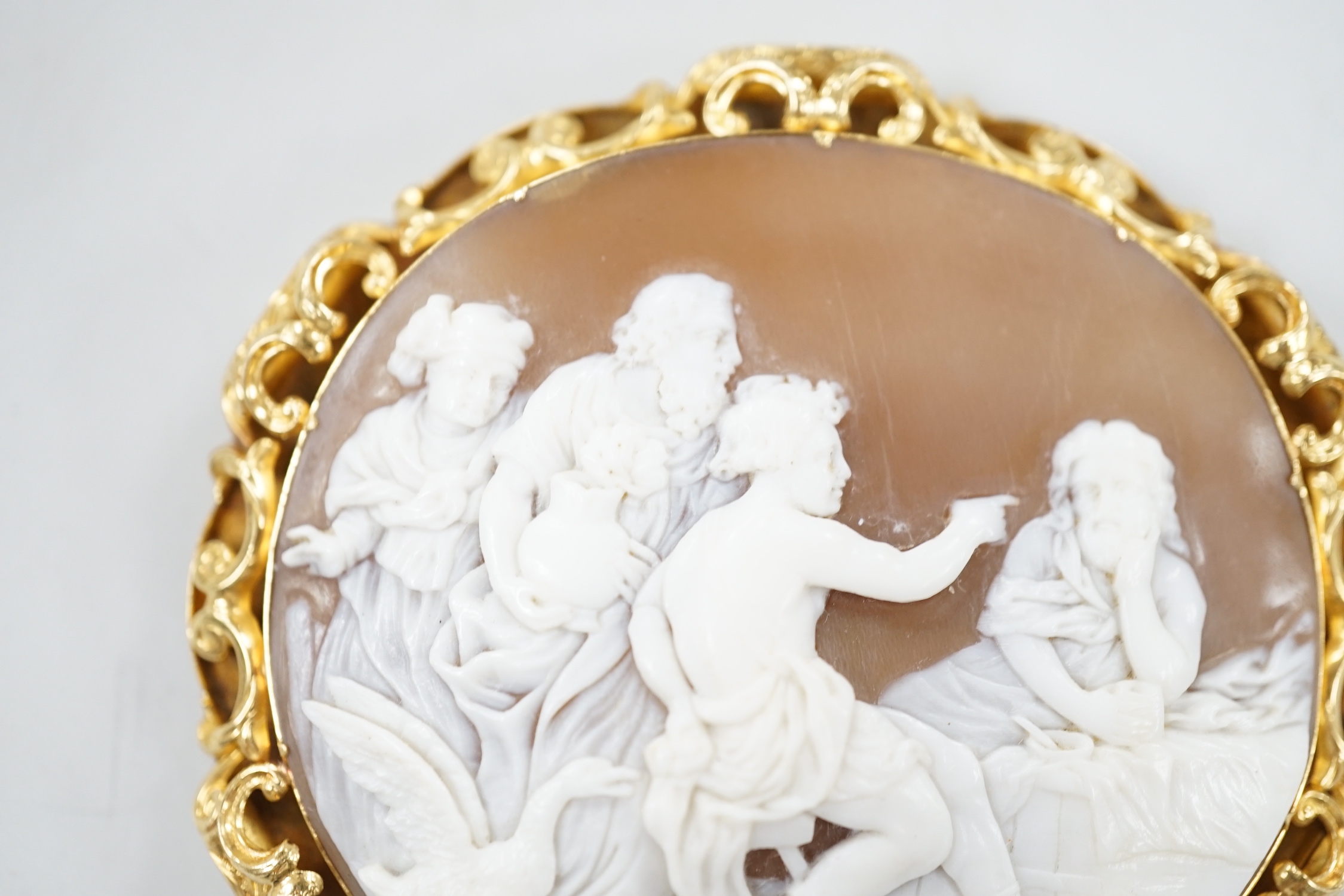 A Victorian yellow metal mounted oval cameo shell brooch, carved with classical figures, width 64mm, gross weight 26.8 grams (pin clasp a.f.).